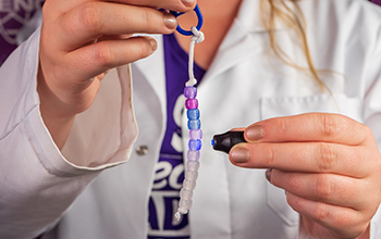 Mad Scientist shining UV light on Sun Bead keychain.