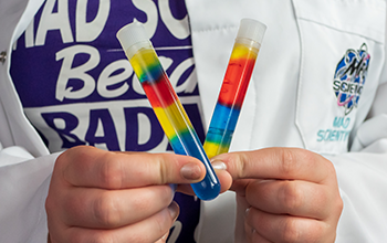 Mad Scientist holding rainbow-colored test tubes.