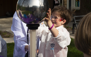 Kid outside playing with a Van de Graaff Generator.