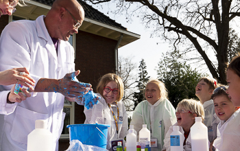 Kids gathered around a table outside making slime with a Mad Scientist. 