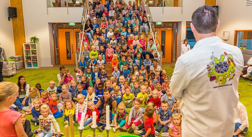Mad scientist performing in front of kids sitting on the floor and up the stairs