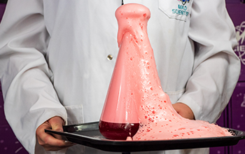 Mad Scientist setting off a baking soda and vinegar volcano in a flask.